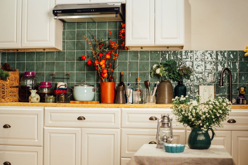 A warm kitchen interior featuring a green tiled backsplash and various kitchenware for a homely feel.